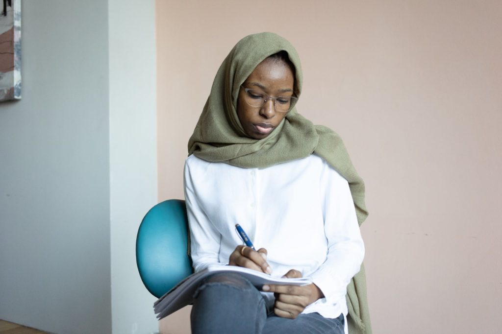 serious black Muslim woman writing in notebook