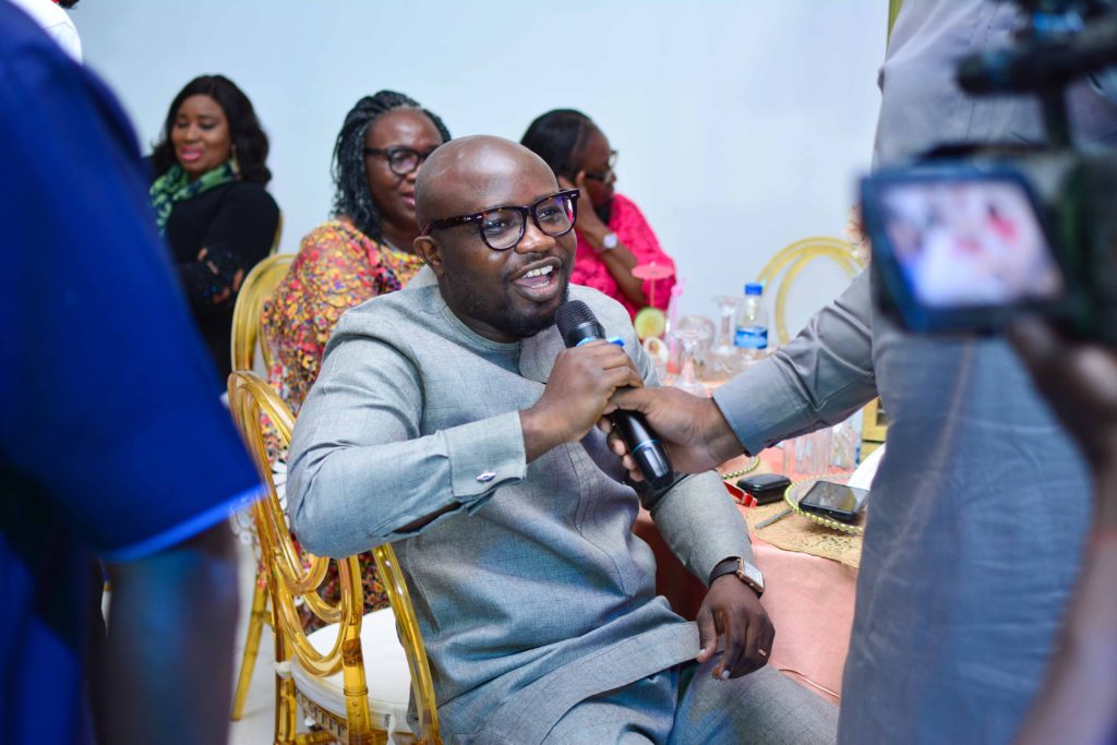 Group of African individuals at an event. Centre is a male holding a microphone to ask a question.